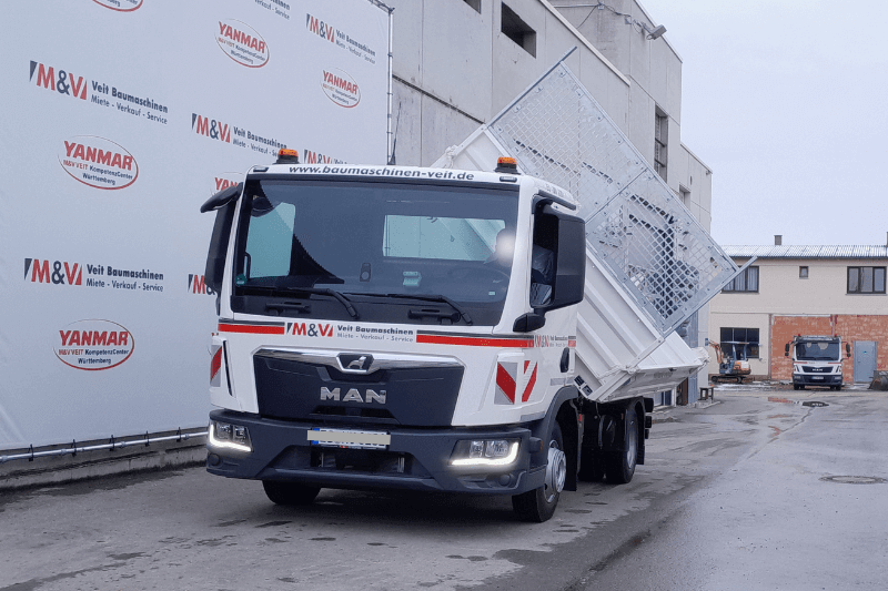 Der MAN TGL 8.190 4X2 BB Kipper in Aktion aus der Frontperspektive mit eingeschalteten Scheinwerfern